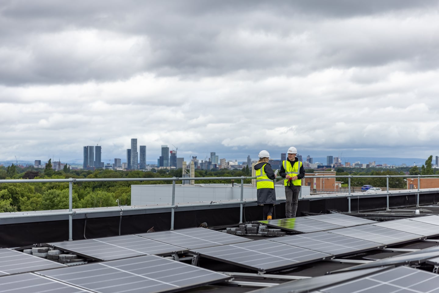 Two workers inspect solar panels on a rooftop.